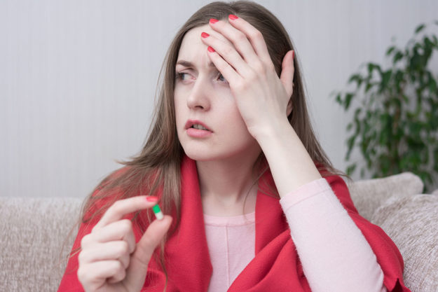 difference between opiates and opioids woman holding pill confused about the difference between opiates and opioids